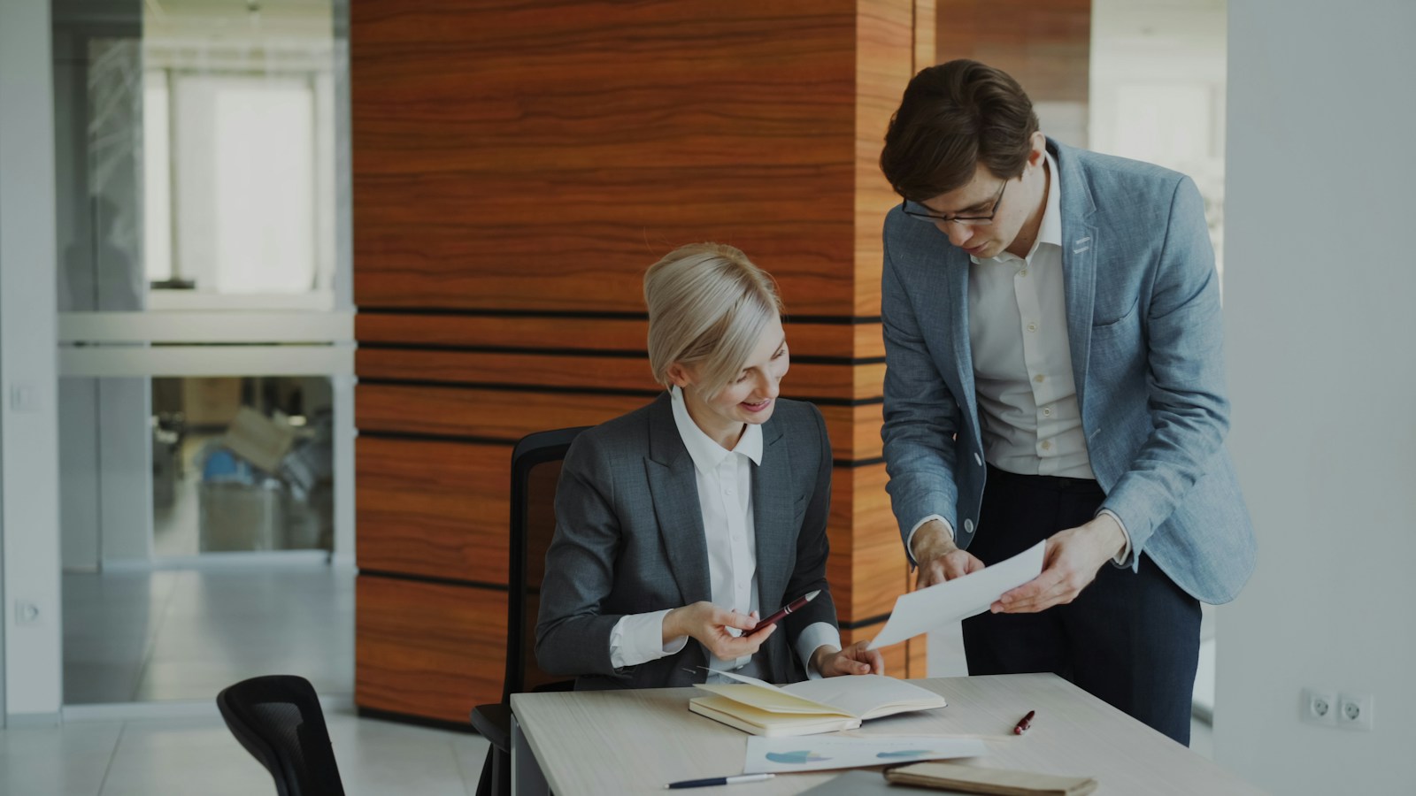Two colleagues discussing documents at an office desk