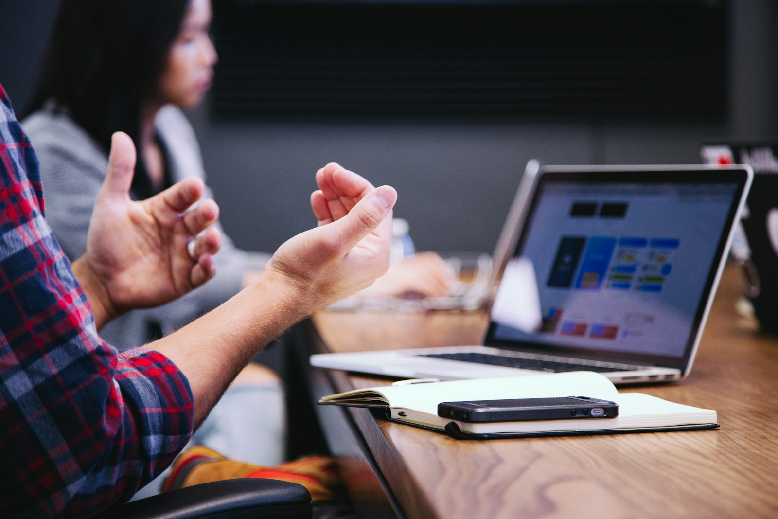 Person gesturing during a meeting with a laptop